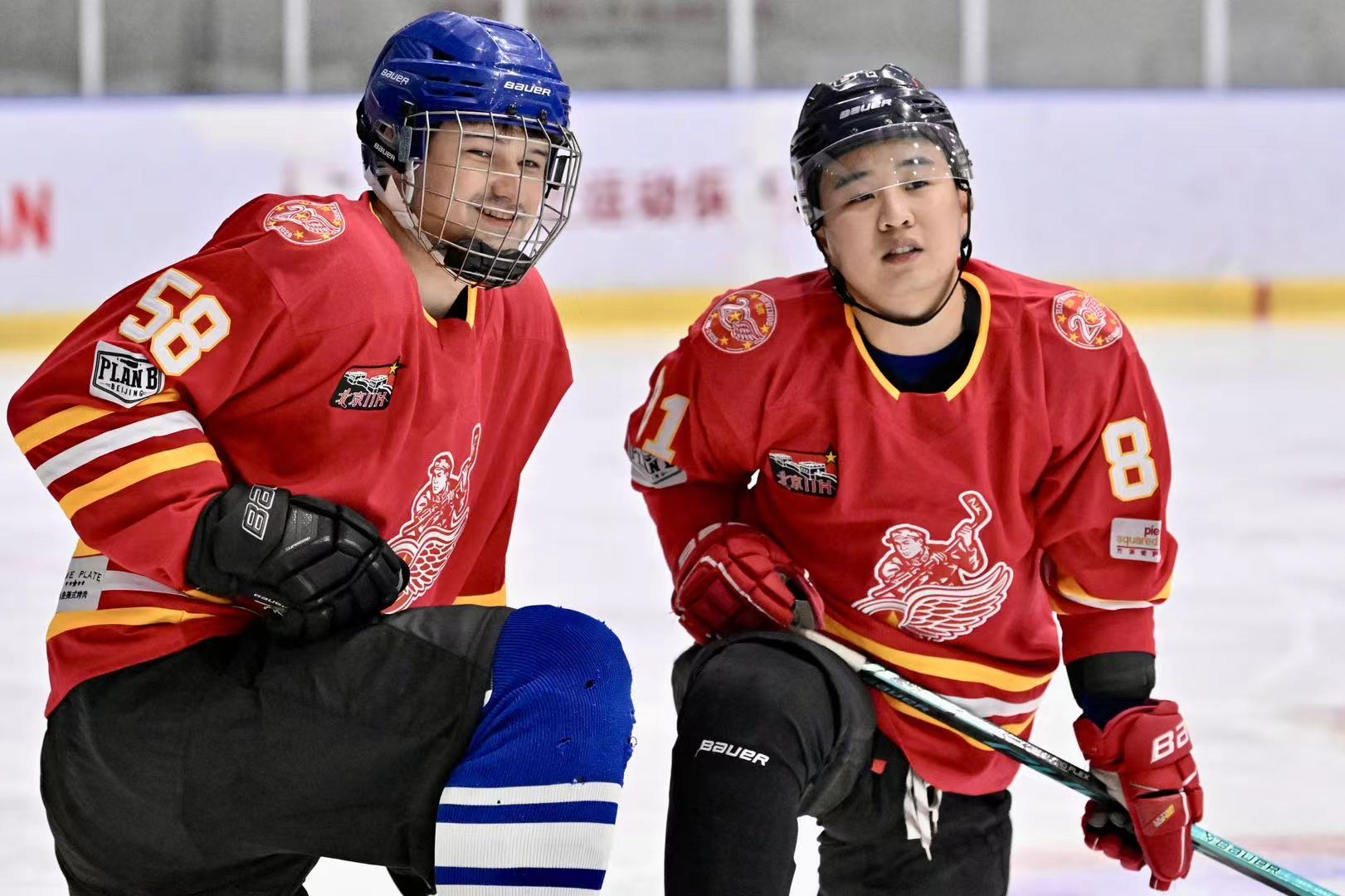 Two Hot Wings players in red jerseys kneeling on the ice