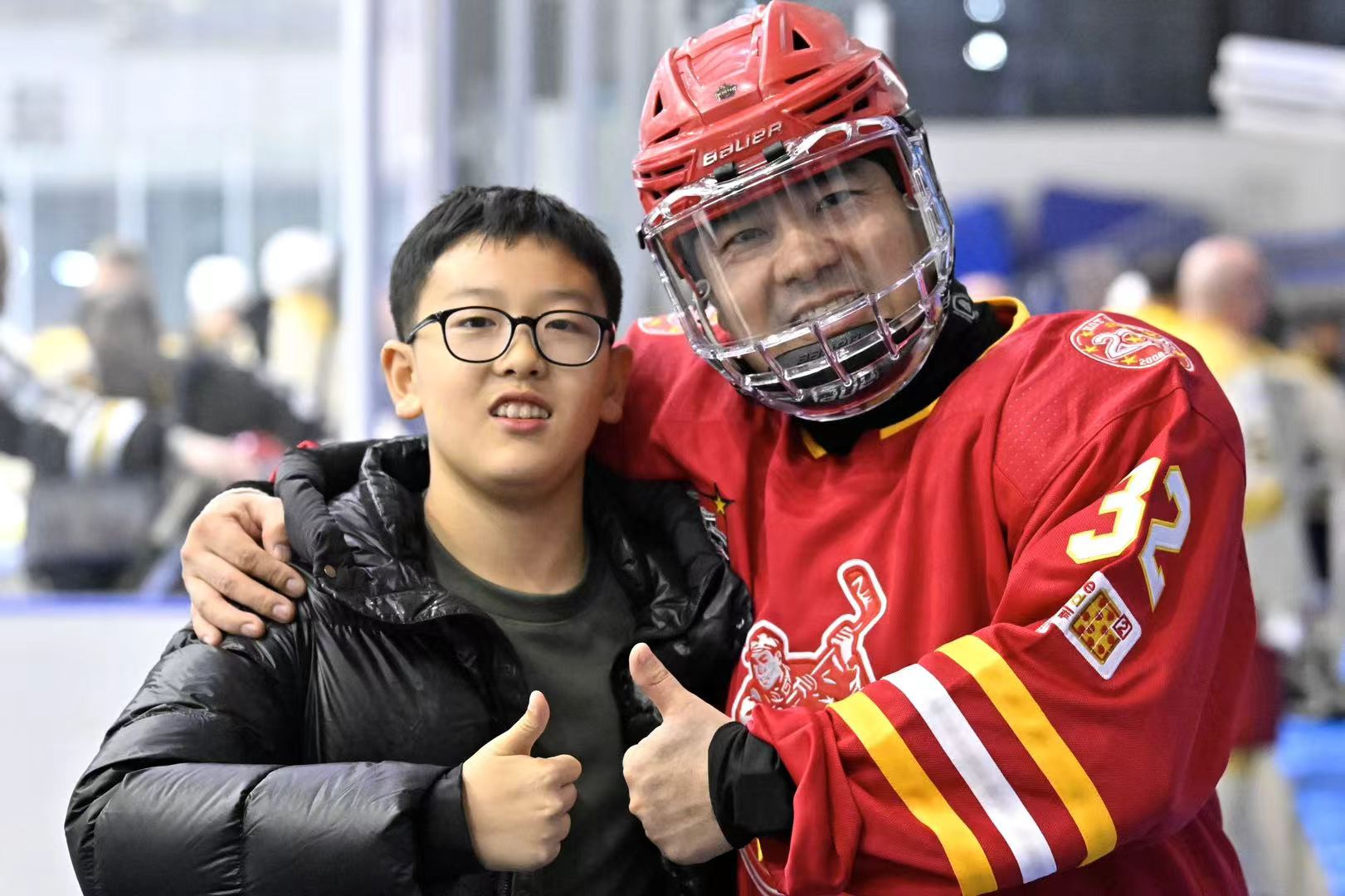 Hot Wings number 32 and a young fan giving thumbs up at the rink
