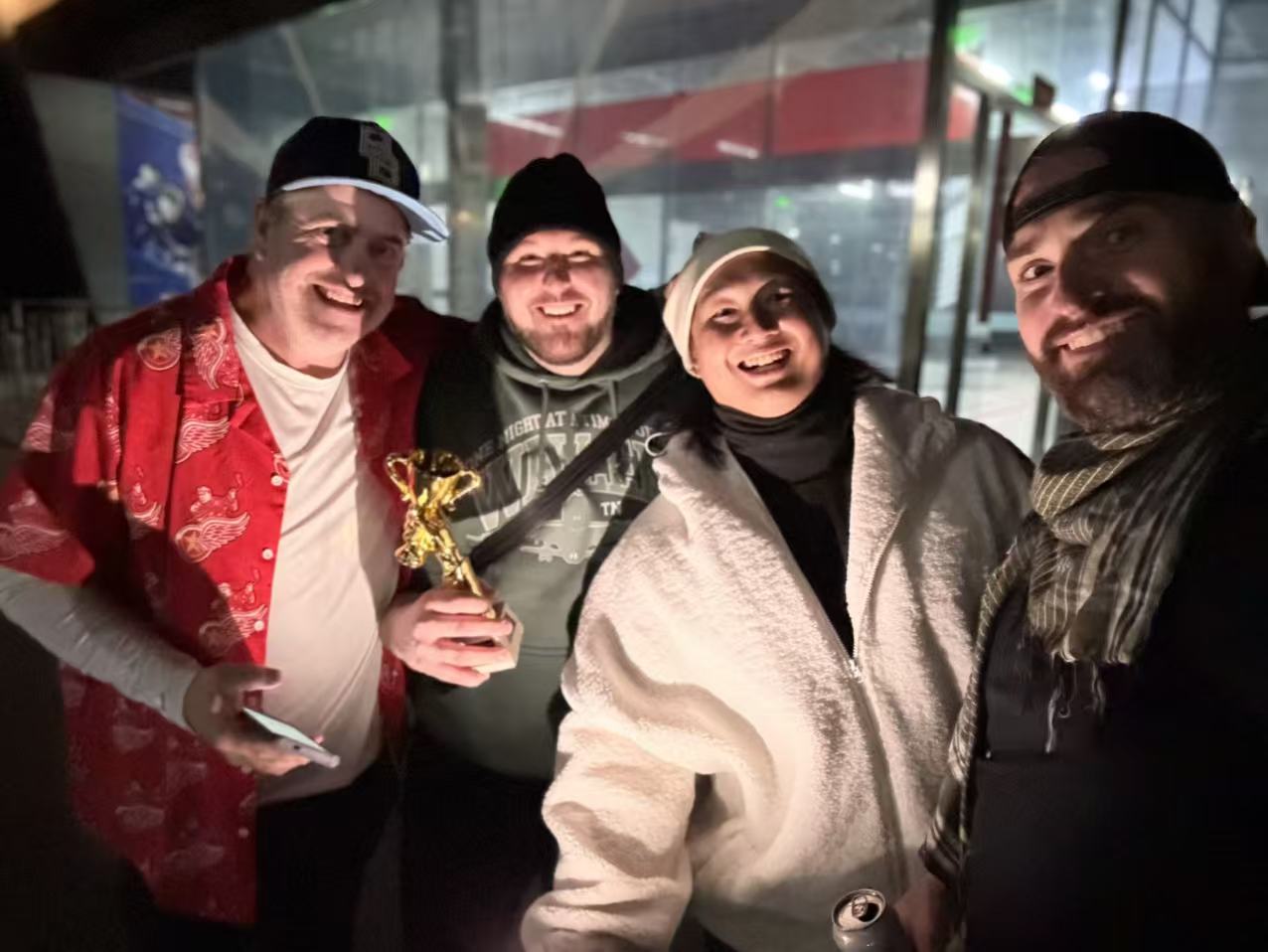 Four friends grinning in the parking lot with dramatic lighting from below